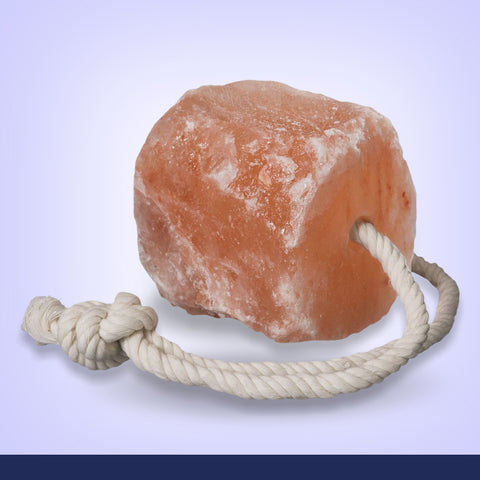 Himalayan salt block with a rope on a light purple background